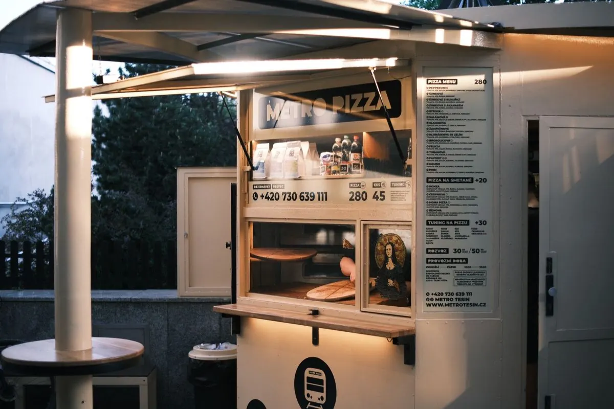 Budka Metro Pizza za šera s rozsvíceným okénkem