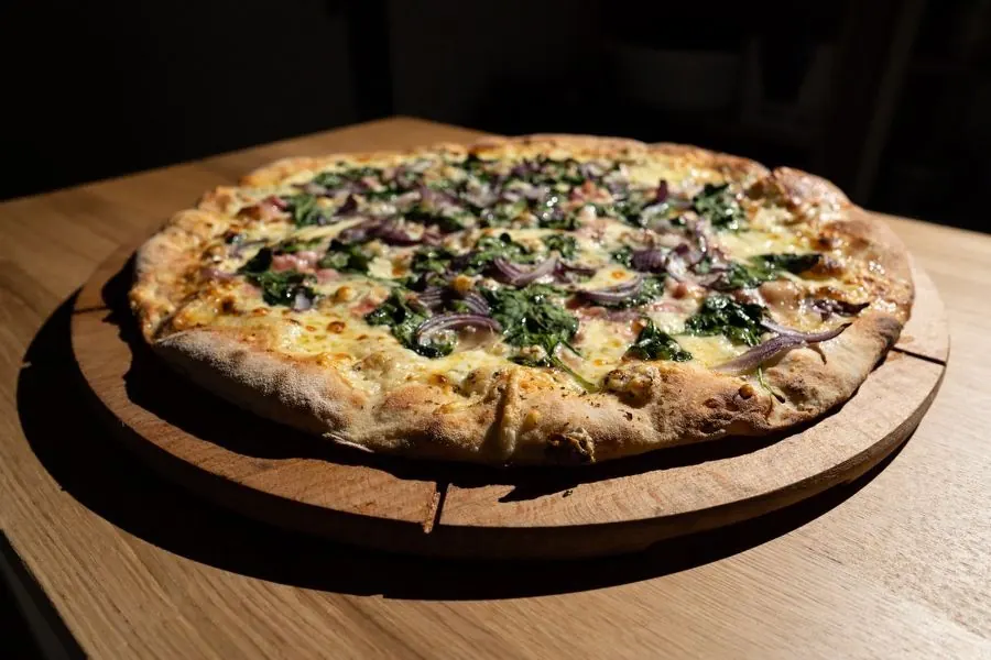 Celá pizza z pece na dřevěném prkénku